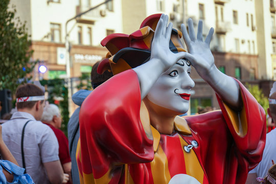Colorful figure of a clown with arms raised.