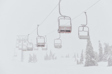 Chairs of a ski lift heading into the fog