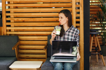 Woman in outdoors street coffee shop wooden cafe sitting in casual clothes, hold laptop pc computer with blank empty screen, relaxing in free time. Mobile Office. Lifestyle freelance business concept.