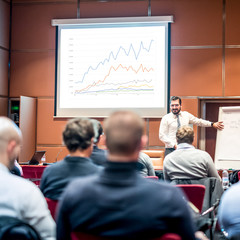 Speaker giving a talk on corporate Business Conference. Audience at the conference hall. Business...