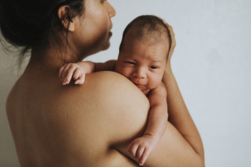 Naked mother holding her infant baby