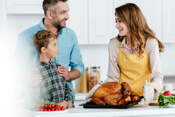 adorable little kid with parents preparing thanksgiving turkey together at kitchen