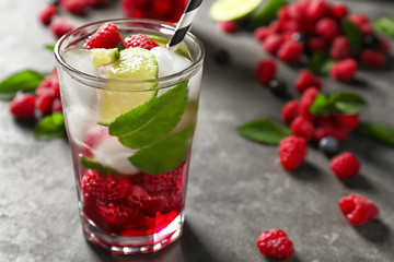 Glass of fresh raspberry mojito on table