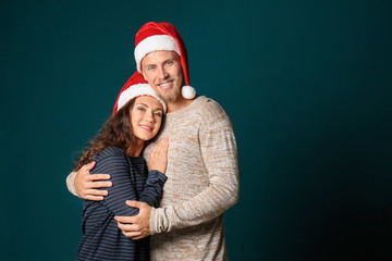 Portrait of cute young couple in Santa hats on color background