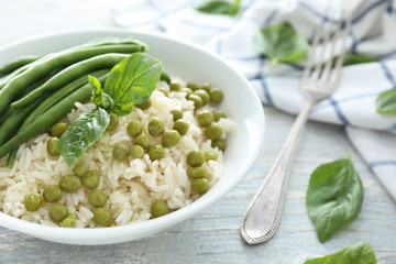Plate with tasty boiled rice and vegetables on light table
