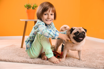 Little boy sitting with cute pug dog on floor at home © Pixel-Shot