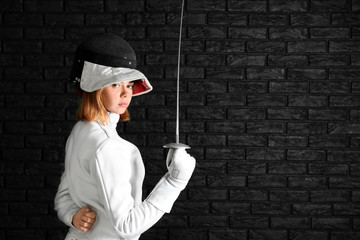 Young female fencer on dark background