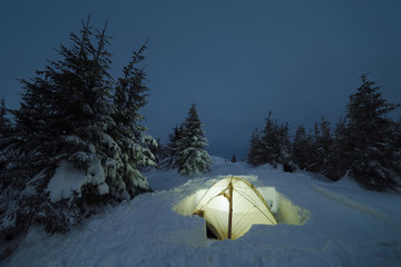 Camping tent in a winter mountain forest