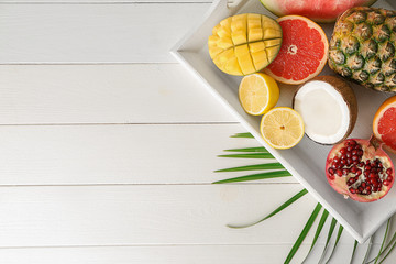 Tray with various delicious exotic fruits on light wooden table