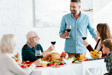 adult man with wine glass making toast while his family having holiday dinner on thanksgiving