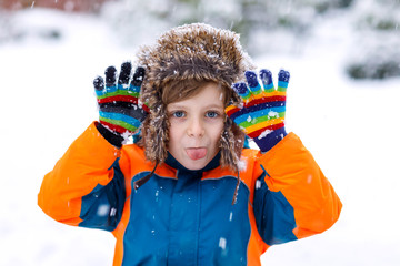 Happy kid boy having fun with snow in winter