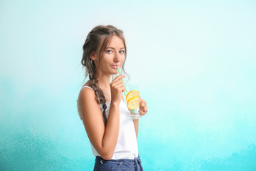 Young woman with glass of fresh lemonade on color background