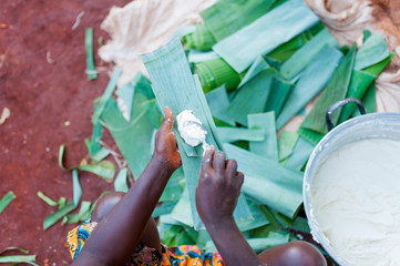 above view of african woman hands making traditonal cameroonian baton de manioc with manioca and...