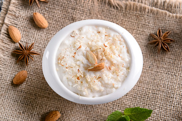 Bowl with delicious rice pudding and almond nuts on sackcloth