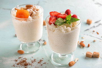 Glasses with delicious rice pudding and fruits on light background
