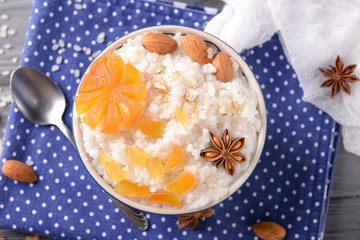Bowl with delicious rice pudding and dry apricots on napkin