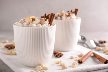 Cups with delicious rice pudding and nuts on napkin
