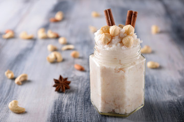 Mason jar with delicious rice pudding and hazelnuts on wooden table
