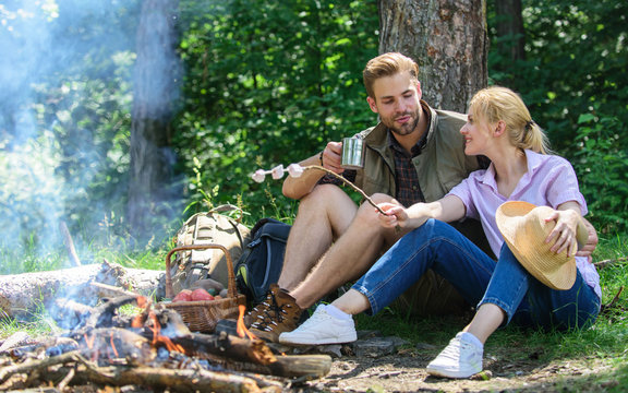 Hike picnic. Couple friends prepare roasted marshmallows snack nature background. Couple in love camping forest roasting marshmallows. Roasting marshmallows at bonfire. Couple eat snacks and drink