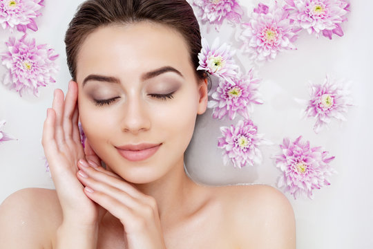 Portrait of young sexy beauty female woman smiling with clean pure skin taking spa relaxing in bath with flowers and white soap shampoo water. Skin beauty health care concept. Body part and nature