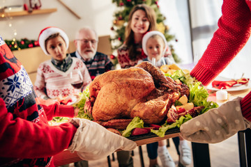 cropped image of people carrying holiday turkey for christmas dinner with family at home