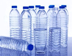 Many plastic water bottles and a glass of water on the table.
