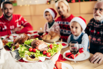 partial view of woman carrying meal for christmas dinner with family at home
