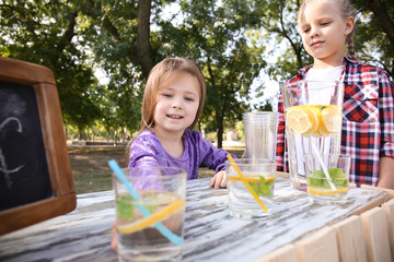 Little girls selling lemonade at counter in park