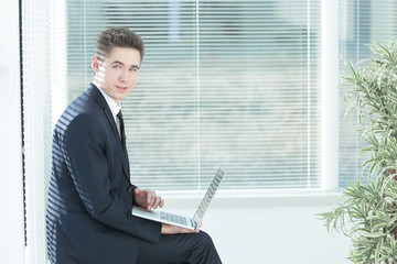 young employee working on a laptop sitting in the corridor of th