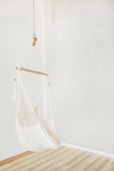 Obraz na płótnie Canvas Cozy white hammock in white room. Minimal home interior design.