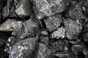 Wet natural black fragments of stones with interspersed marbles for backgrounds, top view. Large broken pieces of stone. Heap of black wet stones