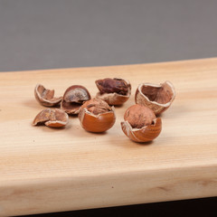Wooden cutting board on grey background with shelled nuts