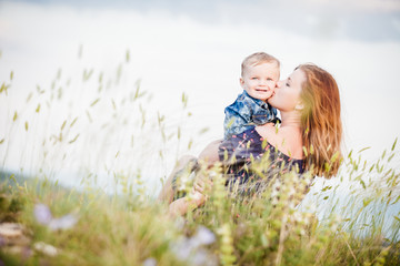 a young mother kisses her son on the cheek