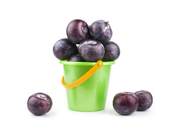 Plums in a green bucket on a white background isolated