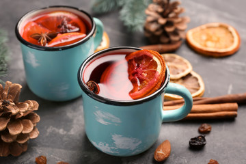 Metal cups of delicious mulled wine on grey table