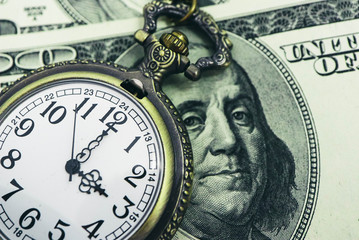 Old pocket watch with American 100 dollar banknotes money with Franklin president portraiture, macro view. Time and business concept.