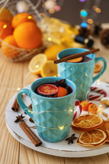 Cups of delicious mulled wine with Christmas garland on wooden table