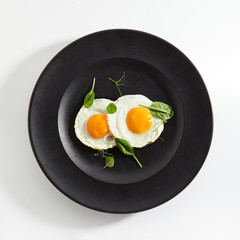 Fried Eggs Decorated with Fresh Spinach Leaves and Young Pea Shoots
