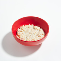 Oatmeal Porridge with Milk in Red Bowl Isolated on White Background
