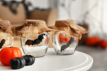 Paper bats in jars with candles as decor for Halloween party on table