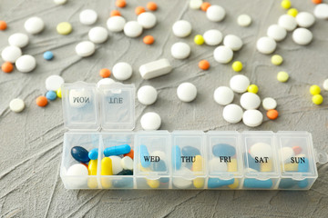 Plastic container with different pills on textured background