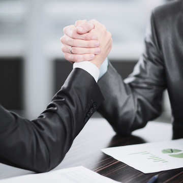 Close Up. Two Businessmen Are Engaged In Arm Wrestling At A Desk