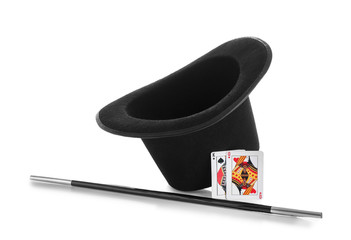 Black hat, magic wand and cards on white background