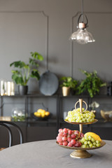 Fruits on round table in grey elegant restaurant interior with lamp. Real photo