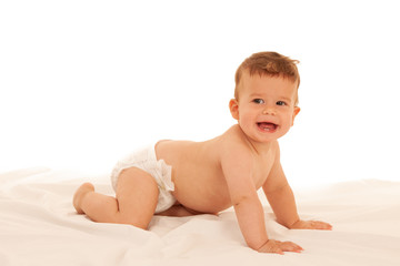Hapy baby boy in playing on bed isolated over white