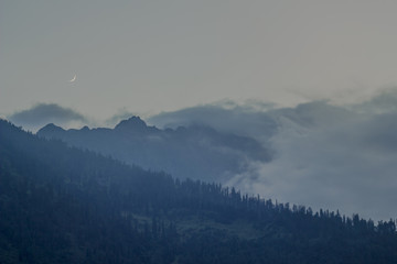 moon in the night sky dark misty mountains