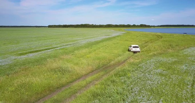 car turns back on grass from lake among fields