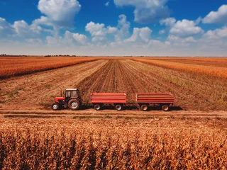 Crédence de cuisine en verre imprimé Tracteur Aerial view of agricultural tractor with cargo carts in field