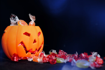 halloween Jack o Lantern candy collector full of candy and some scattered sweets on the black...