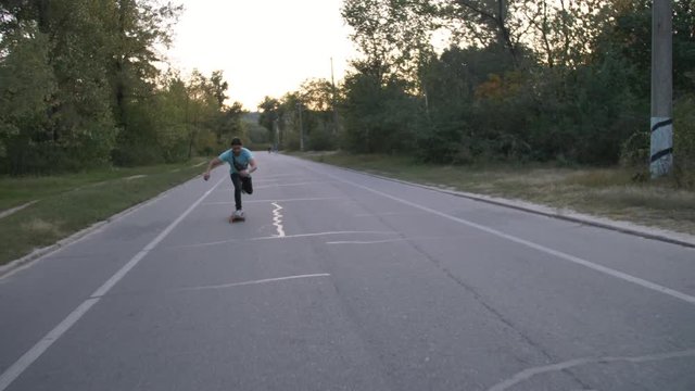 Mixed race hipster man longboarder racing in city public park in slow motion